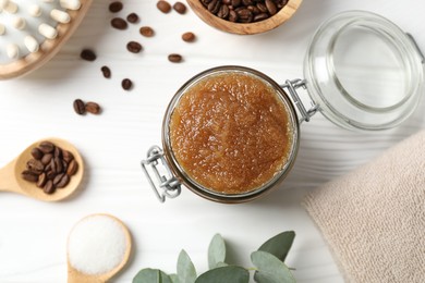 Photo of Natural body scrub in glass jar, ingredients and brush on white wooden table, flat lay
