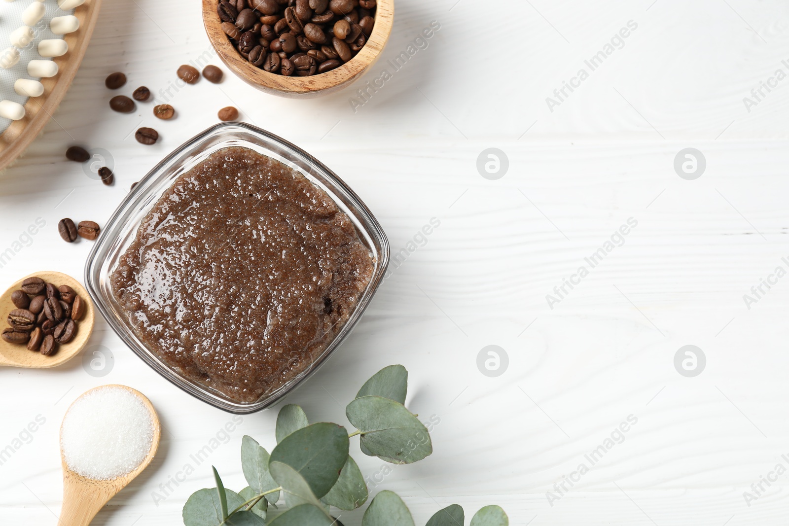 Natural body scrub in glass bowl, ingredients and brush on white wooden table, flat lay. Space for text Photo of Natural body scrub in glass bowl, ingredients and brush on white wooden table, flat lay. Space for text