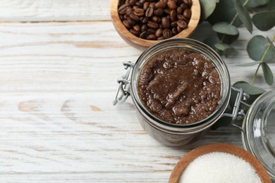 Photo of Natural body scrub in glass jar and ingredients on wooden table, above view. Space for text