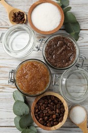 Photo of Natural body scrubs in glass jars and ingredients on wooden table, flat lay