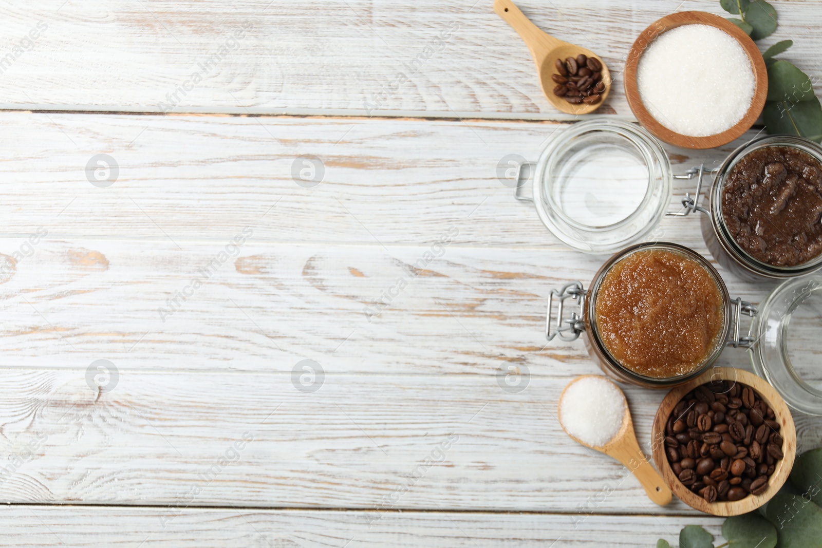 Photo of Natural body scrubs in glass jars and ingredients on wooden table, flat lay. Space for text