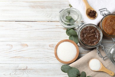 Photo of Natural body scrubs in glass jars and ingredients on wooden table, flat lay. Space for text