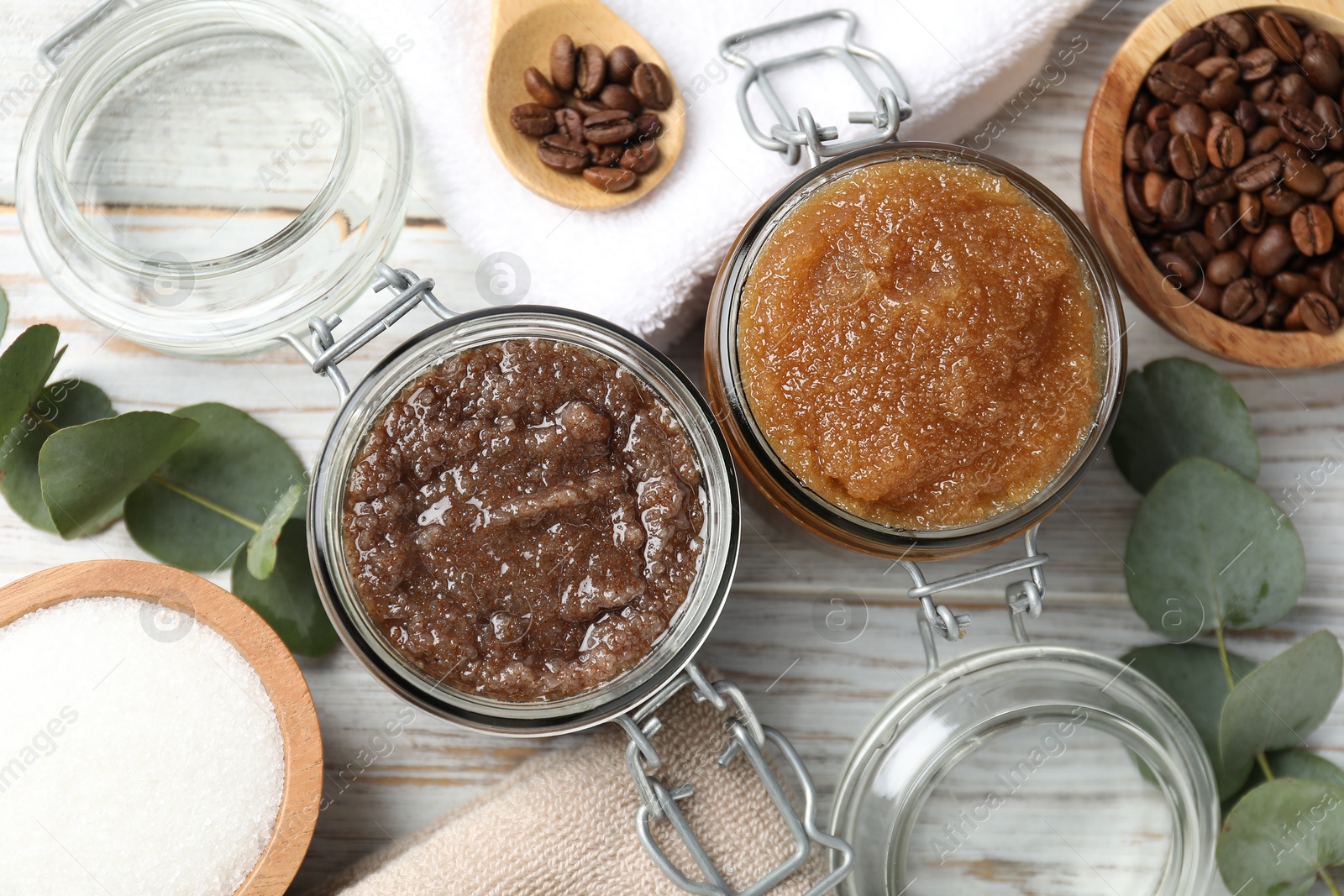 Photo of Natural body scrubs in glass jars and ingredients on wooden table, flat lay