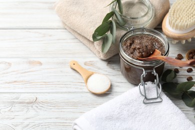 Photo of Natural body scrub in glass jar, ingredients, brush and towels on wooden table, closeup. Space for text