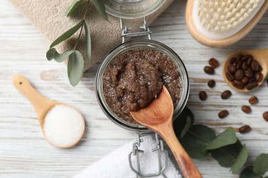 Photo of Natural body scrub in glass jar, ingredients, brush and towels on wooden table, flat lay