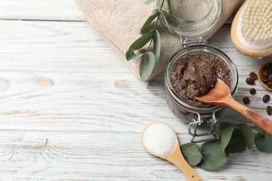 Photo of Natural body scrub in glass jar, ingredients, brush and towel on wooden table, above view. Space for text