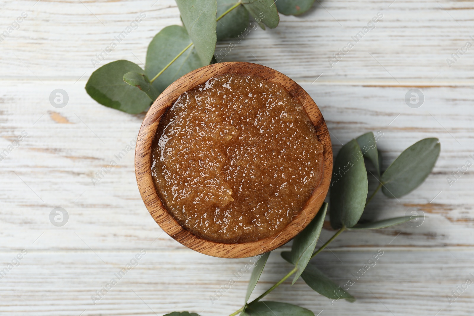 Natural body scrub in bowl and eucalyptus branches on wooden table, flat lay Photo of Natural body scrub in bowl and eucalyptus branches on wooden table, flat lay