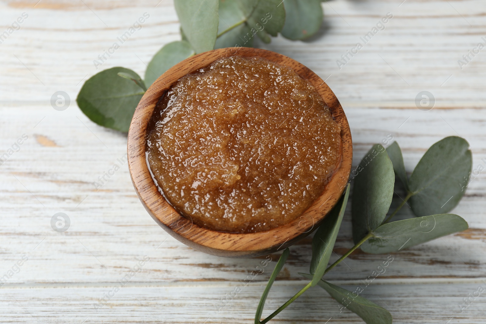 Natural body scrub in bowl and eucalyptus branches on wooden table, above view Photo of Natural body scrub in bowl and eucalyptus branches on wooden table, above view