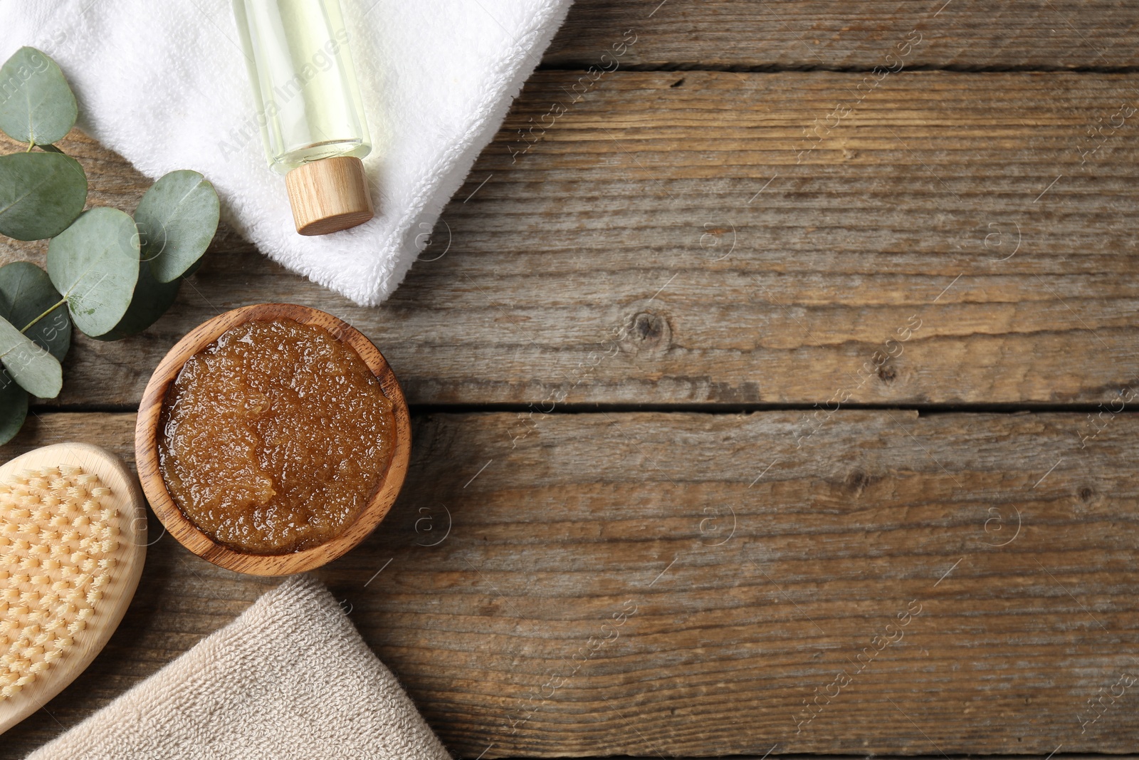 Natural body scrub in bowl, ingredients, brush and towels on wooden table, flat lay. Space for text Photo of Natural body scrub in bowl, ingredients, brush and towels on wooden table, flat lay. Space for text