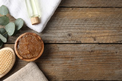 Photo of Natural body scrub in bowl, ingredients, brush and towels on wooden table, flat lay. Space for text