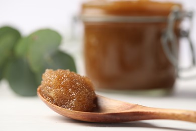 Photo of Natural body scrub in spoon on white table, closeup