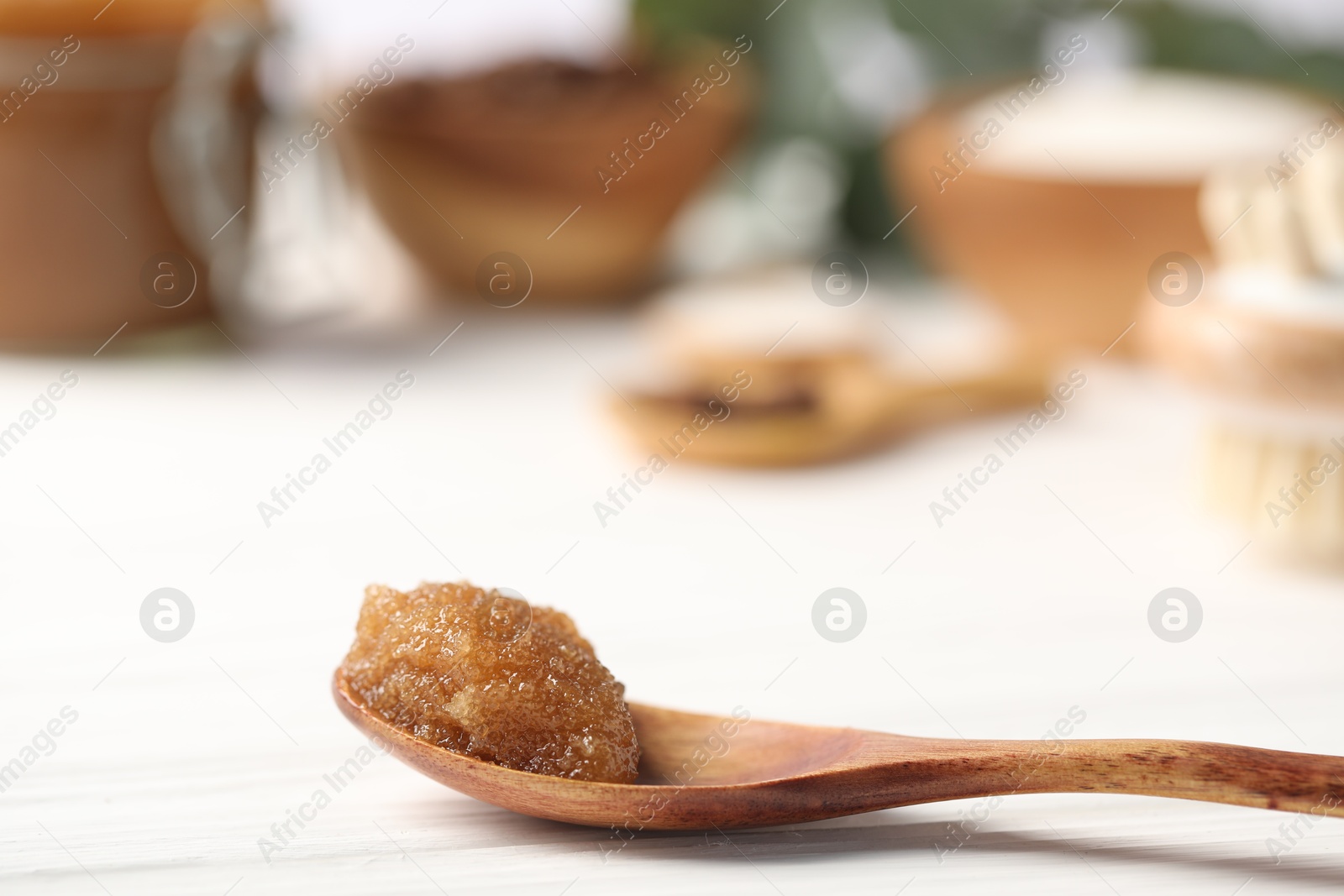 Natural body scrub in spoon on white wooden table, closeup Photo of Natural body scrub in spoon on white wooden table, closeup