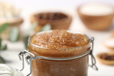 Photo of Natural body scrub in glass jar on blurred background, closeup
