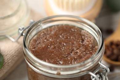 Photo of Natural body scrub in glass jar on table, closeup
