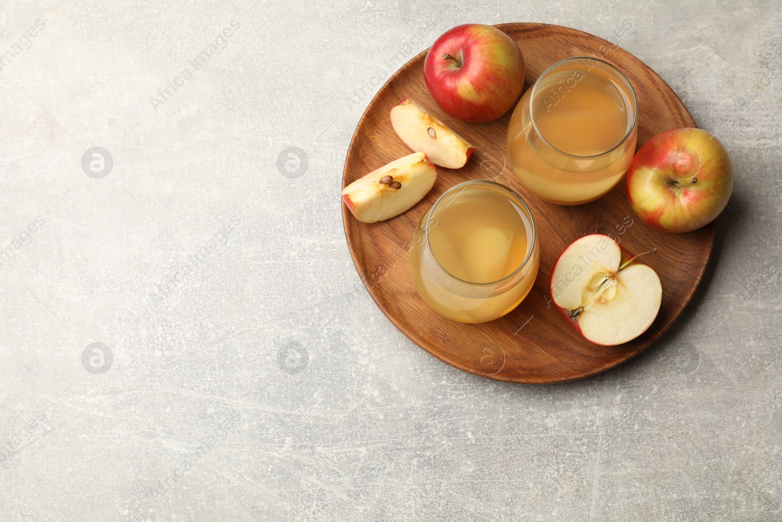 Photo of Tasty compot in glasses and fresh apples on grey table, top view. Space for text