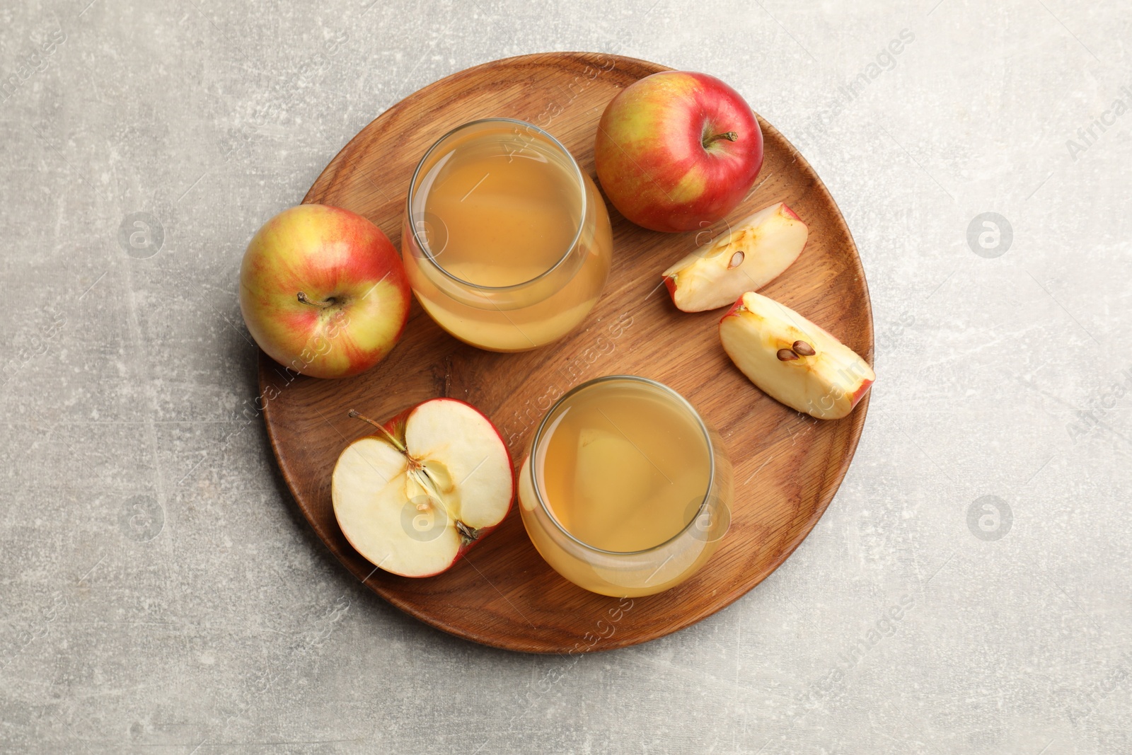 Photo of Tasty compot in glasses and fresh apples on grey table, top view