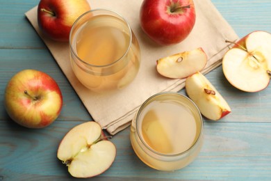 Photo of Tasty compot in glasses and fresh apples on light blue wooden table, flat lay