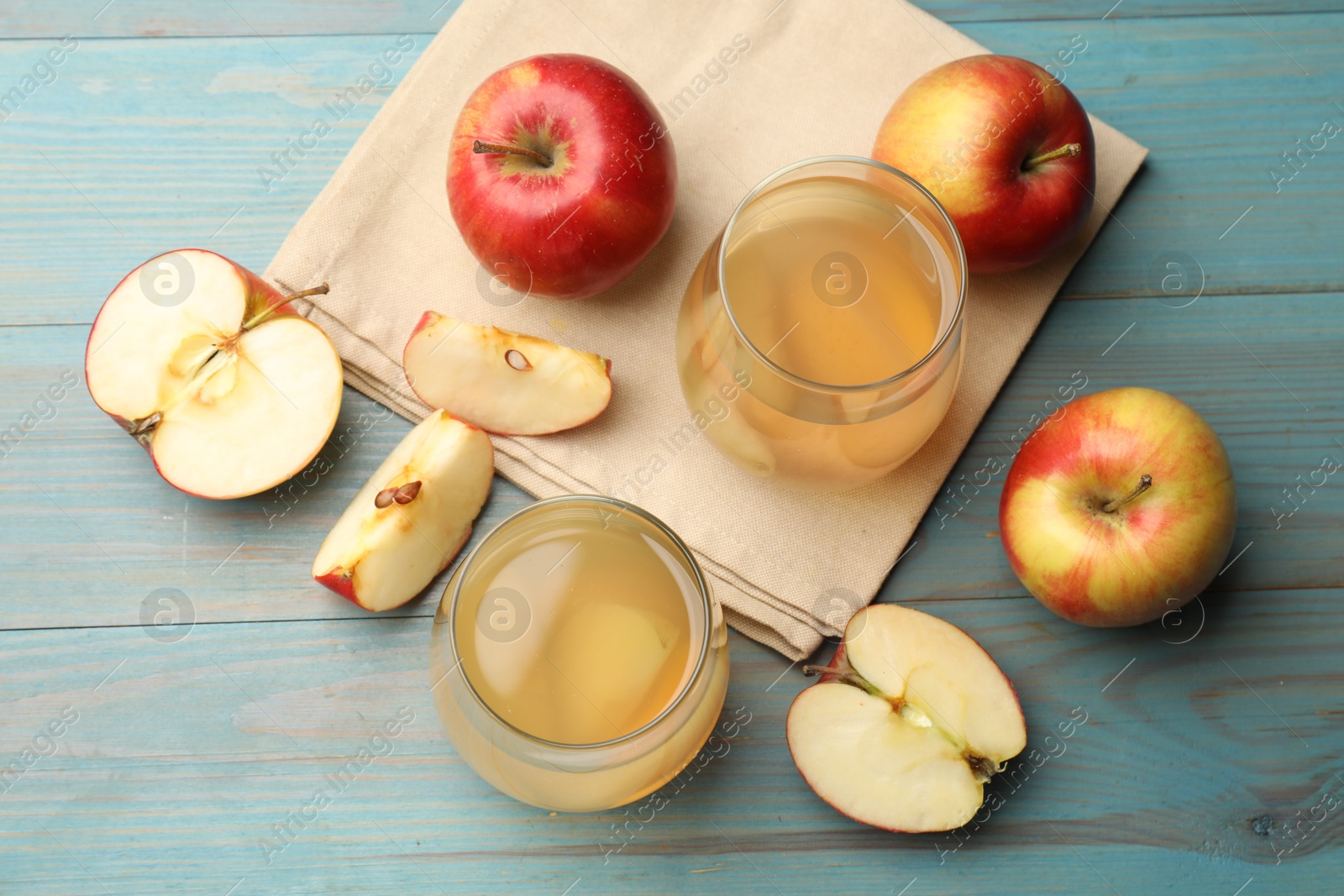 Photo of Tasty compot in glasses and fresh apples on light blue wooden table, flat lay
