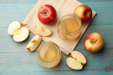 Photo of Tasty compot in glasses and fresh apples on light blue wooden table, flat lay