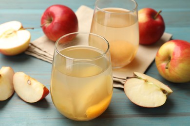 Photo of Tasty compot in glasses and fresh apples on light blue wooden table, closeup