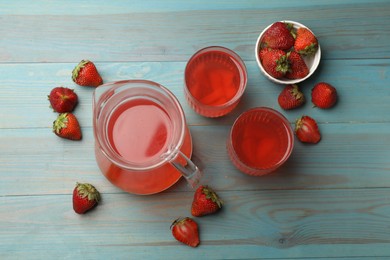 Photo of Tasty compot in glasses, jug and fresh strawberries on light blue wooden table, flat lay