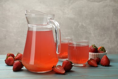 Photo of Tasty compot in glasses, jug and fresh strawberries on light blue wooden table