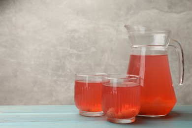 Photo of Tasty compot in glasses and jug on light blue wooden table, space for text