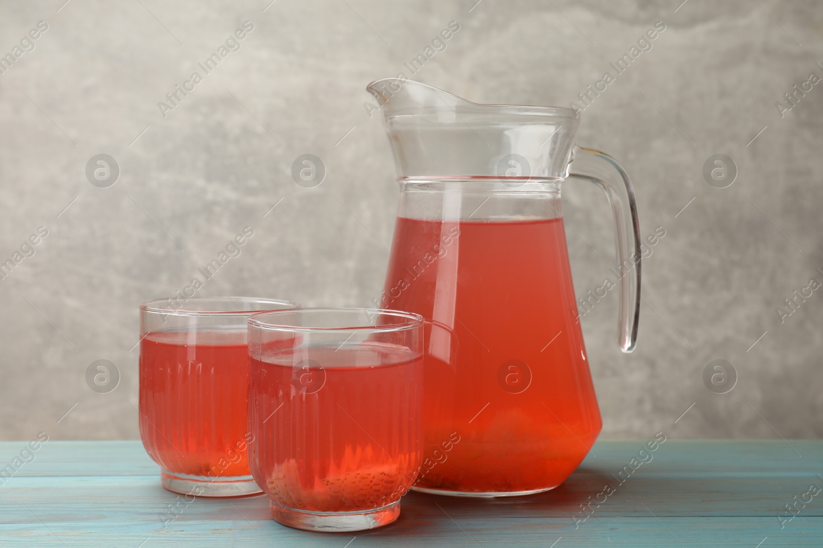 Photo of Tasty compot in glasses and jug on light blue wooden table
