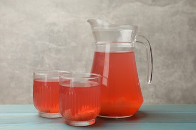 Photo of Tasty compot in glasses and jug on light blue wooden table