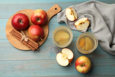 Photo of Tasty compot in glasses, fresh apples and cinnamon on light blue wooden table, flat lay