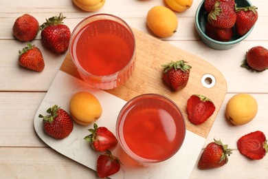 Photo of Tasty compot in glasses, fresh strawberries and apricots on wooden table, flat lay