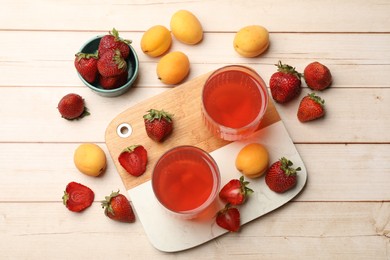 Photo of Tasty compot in glasses, fresh strawberries and apricots on wooden table, flat lay