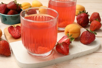 Photo of Tasty compot in glasses, fresh strawberries and apricots on wooden table, closeup