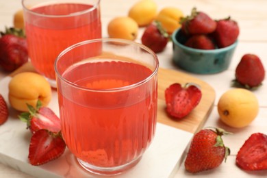 Photo of Tasty compot in glasses, fresh strawberries and apricots on wooden table, closeup