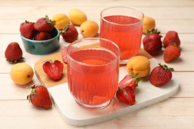 Photo of Tasty compot in glasses, fresh strawberries and apricots on wooden table, closeup