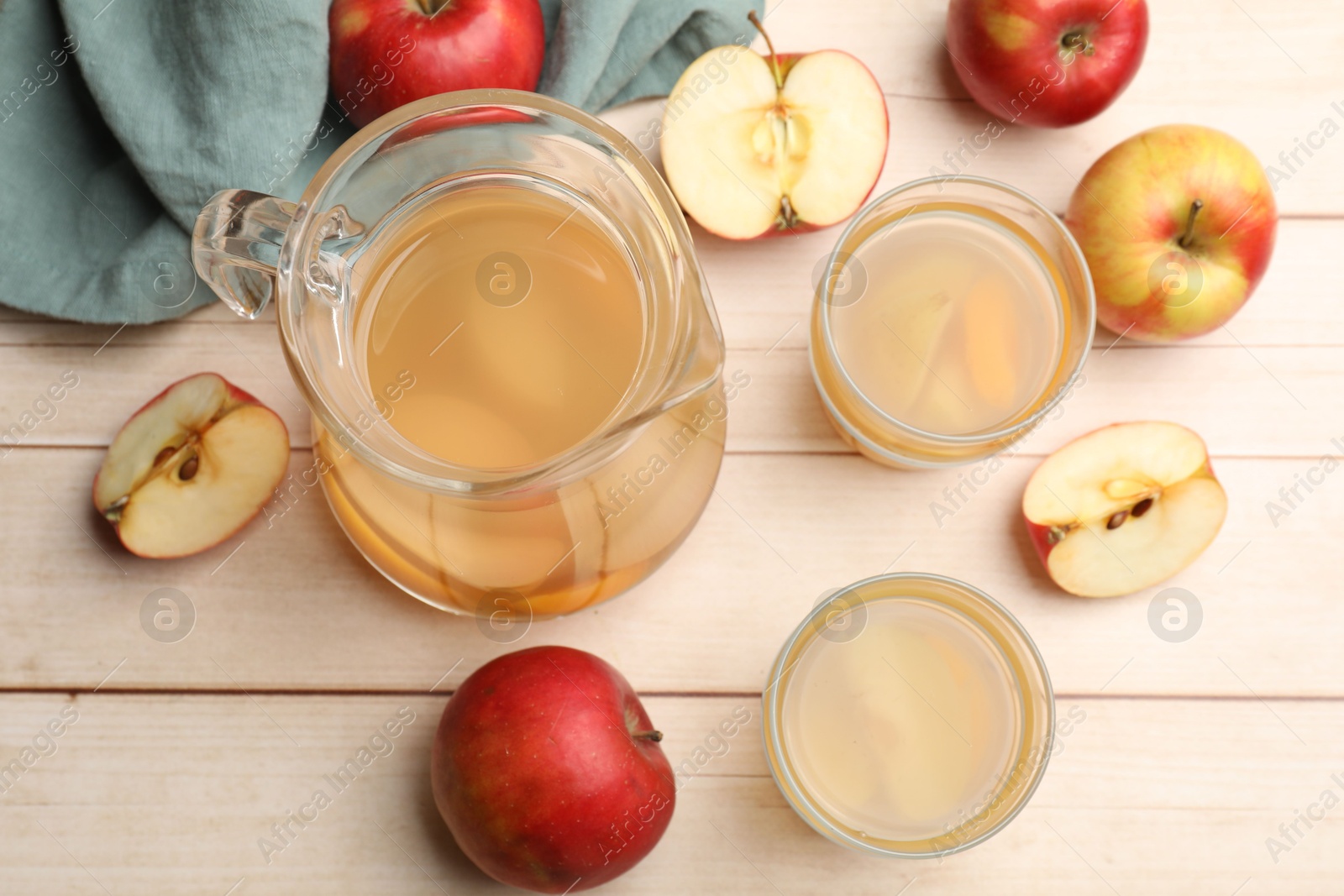 Photo of Tasty compot in glasses, jug and fresh apples on wooden table, flat lay