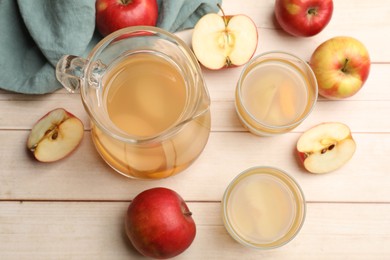 Photo of Tasty compot in glasses, jug and fresh apples on wooden table, flat lay