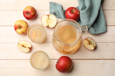 Photo of Tasty compot in glasses, jug and fresh apples on wooden table, flat lay