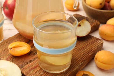 Photo of Tasty compot in glass and fresh apricots on table, closeup