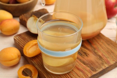 Photo of Tasty compot in glass and fresh apricots on table, closeup