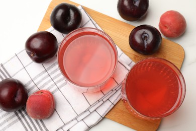 Photo of Tasty compot in glasses, plums and apricots on white marble table, flat lay