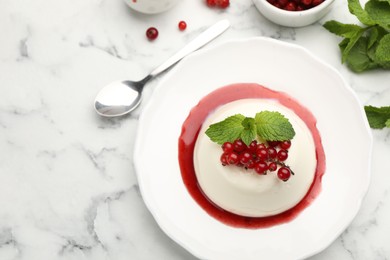 Photo of Delicious panna cotta with red currants, sauce and mint on white marble table, flat lay
