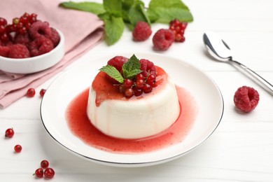 Photo of Delicious panna cotta with berries, sauce and mint on white wooden table, closeup