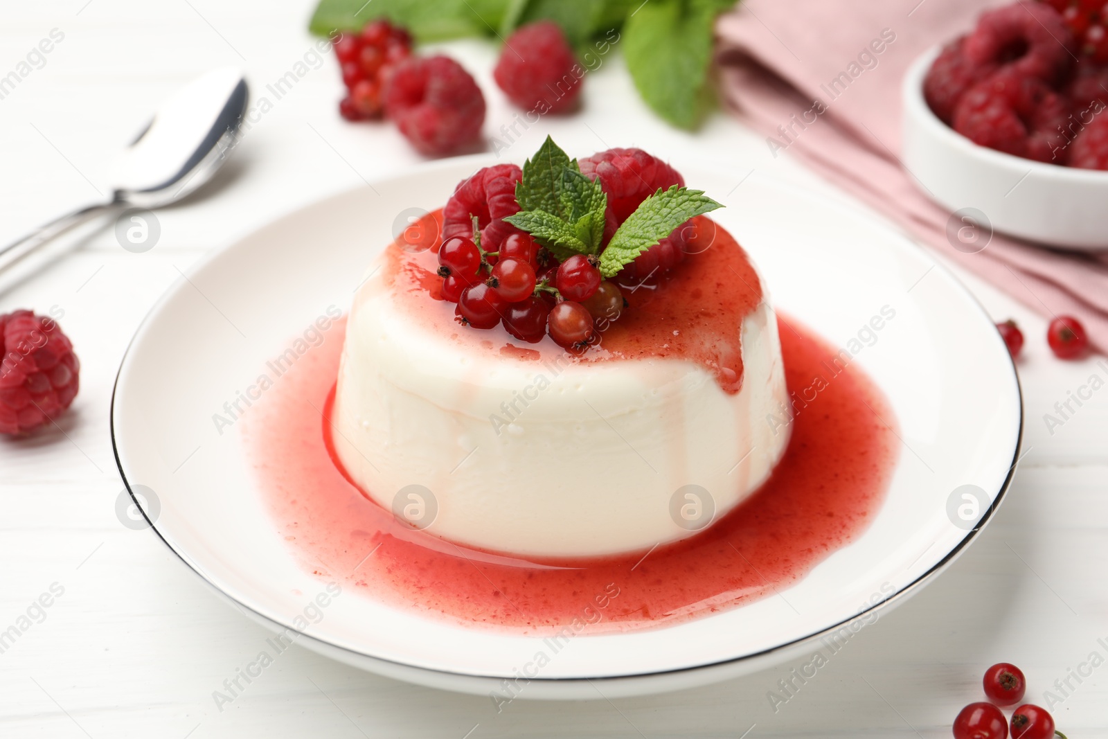 Delicious panna cotta with berries, sauce and mint on white wooden table, closeup Photo of Delicious panna cotta with berries, sauce and mint on white wooden table, closeup