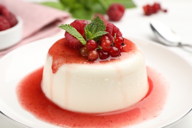 Photo of Delicious panna cotta with berries, sauce and mint on white table, closeup