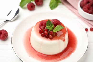 Photo of Delicious panna cotta with berries, sauce and mint on white wooden table, closeup