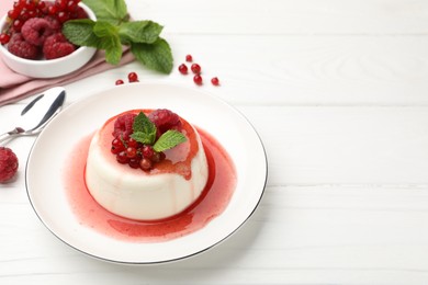 Photo of Delicious panna cotta with berries, sauce and mint on white wooden table, closeup. Space for text