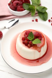 Photo of Delicious panna cotta with berries, sauce and mint on white wooden table, closeup