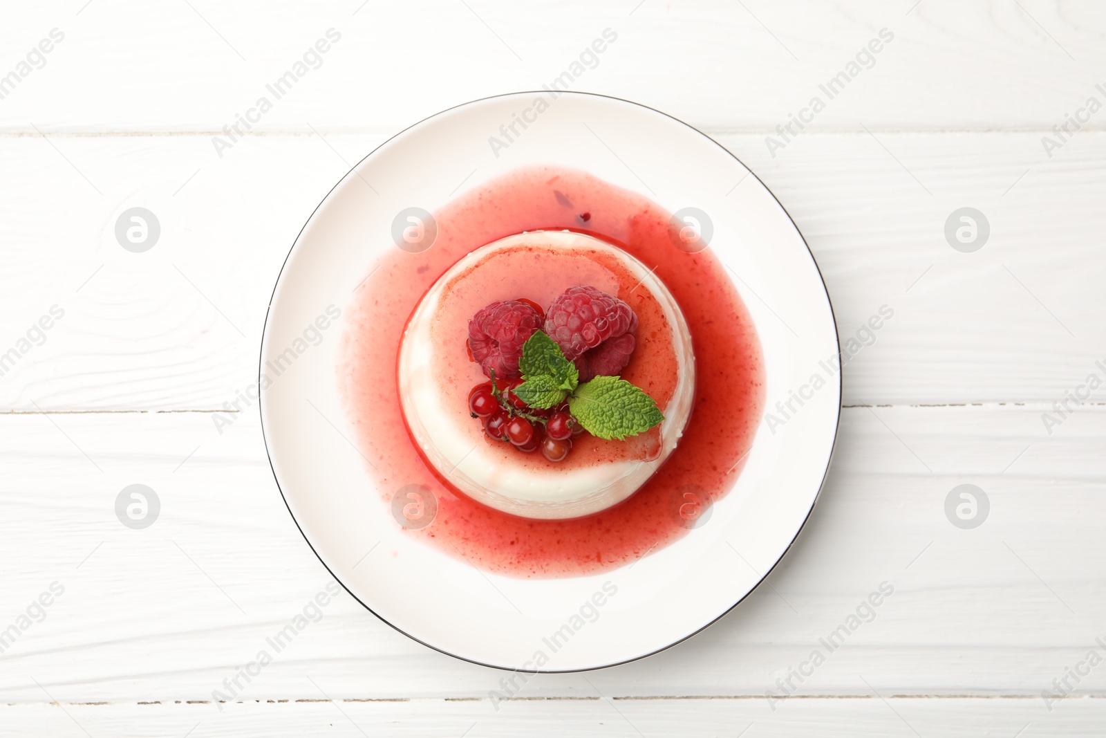 Delicious panna cotta with berries, sauce and mint on white wooden table, top view Photo of Delicious panna cotta with berries, sauce and mint on white wooden table, top view