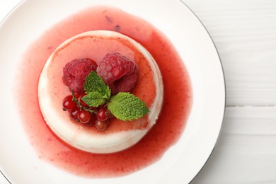 Photo of Delicious panna cotta with berries, sauce and mint on white wooden table, top view